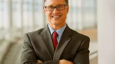 Gülümseyen bir iş adamı, takım elbise ve kırmızı kravatla poz veriyor.