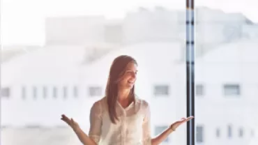 Kadın bir sunum yapıyor, ofis toplantısında konuşuyor.