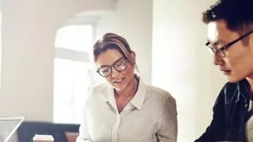 Two people working at an office desk.