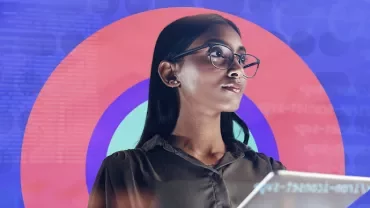 Woman with glasses holding a tablet, colorful circle and code background.