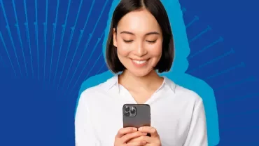 Genç kadın mavi arka planda telefonuna bakıyor.