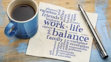 Coffee cup, pen, and napkin with words about work-life balance.