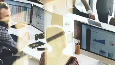 Office workers analyzing data on computer screens.
