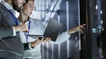 Two people working in a data center with a laptop.