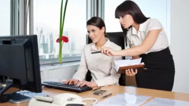 Two women in an office looking at a computer screen.