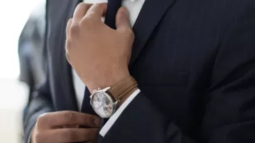 A person in a suit adjusting a striped tie