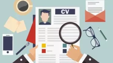 A hand examines a resume with a magnifying glass.