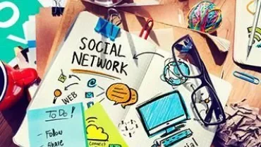 Notebook with social media icons and doodles on a desk.