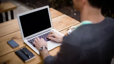 Person using a laptop on a wooden table.