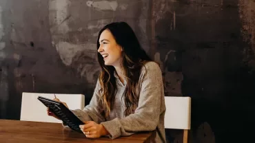 Woman laughing while holding a tablet.