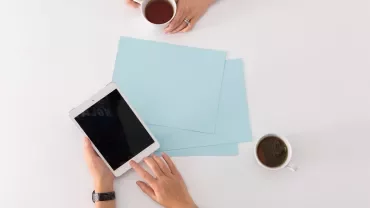Two people at a table with a tablet and tea.