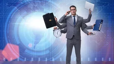 Bir ofis çalışanı, ellerinde çanta, saat, dosya ve dizüstü bilgisayarla çoklu görev yapıyor.