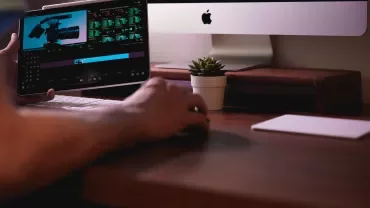 Masaüstünde bilgisayar ve video düzenleyen bir tablet.