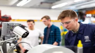 Young engineer with safety glasses working on machinery.