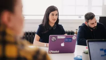 Woman sitting at a meeting with a laptop.