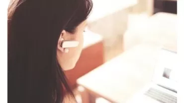 Woman using a laptop with a headset on.