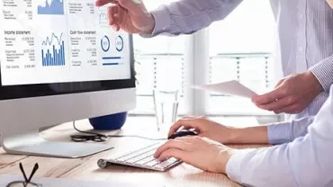 Two people reviewing a financial report on a computer screen.