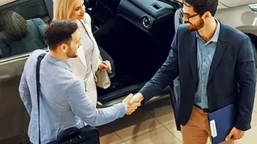 Two men shaking hands while a woman watches.