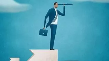 Businessman using a telescope atop a peak.