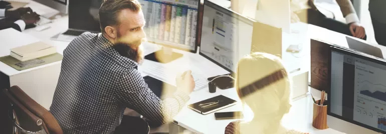 Ofis ortamında bilgisayarlarla çalışan iki kişi.