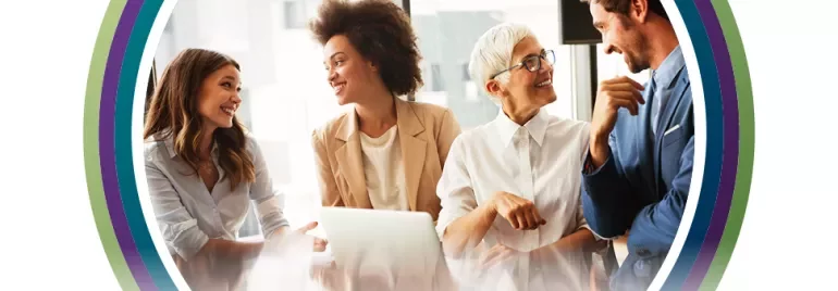 Four people smiling and chatting in an office.