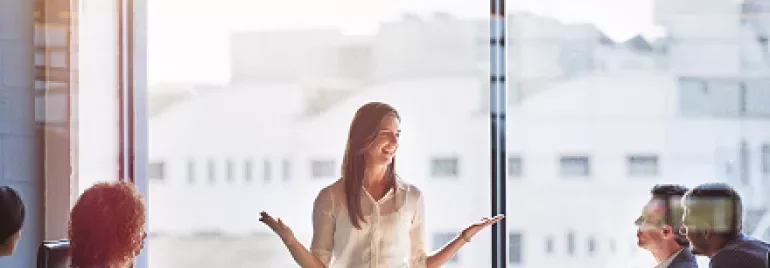 Kadın bir sunum yapıyor, ofis toplantısında konuşuyor.