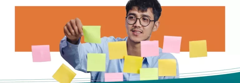 Man organizing colorful sticky notes on a wall.