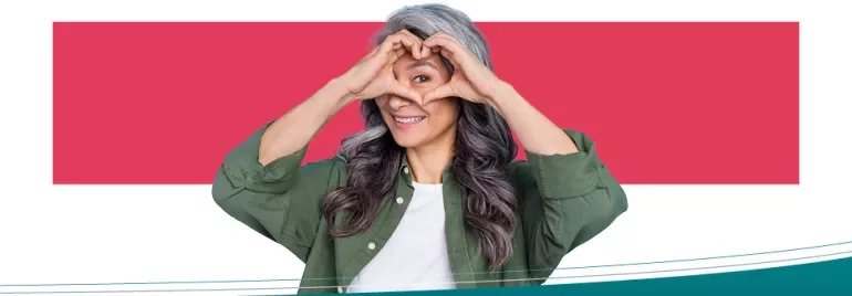 Woman smiling while making a heart shape with her hands.