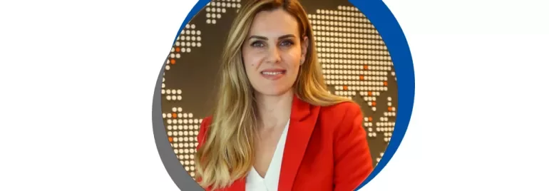 Kırmızı ceketli, beyaz bluzlu bir kadın.