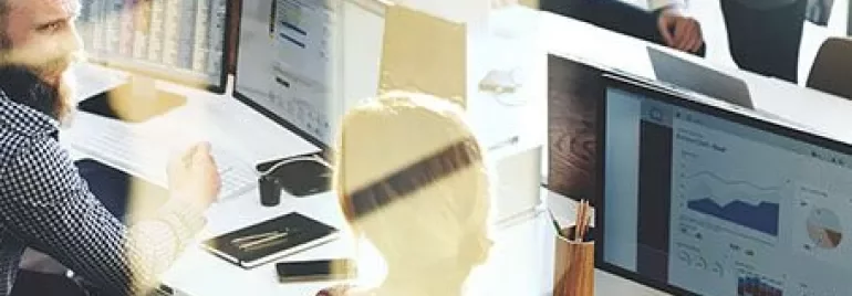 Office workers analyzing data on computer screens.