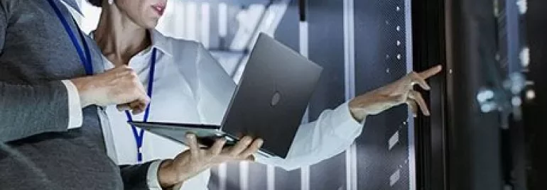Two people working in a data center with a laptop.