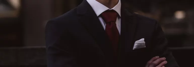 Koyu takım elbiseli ve kravatlı erkek, kolları bağlı.