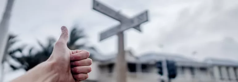 Başparmak hareketiyle belirsiz bir arka plan önünde poz veren bir el.