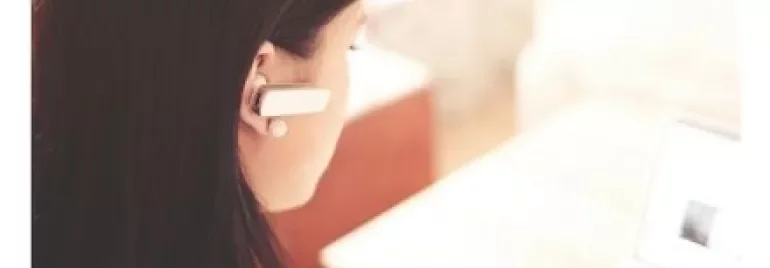 Woman using a laptop with a headset on.