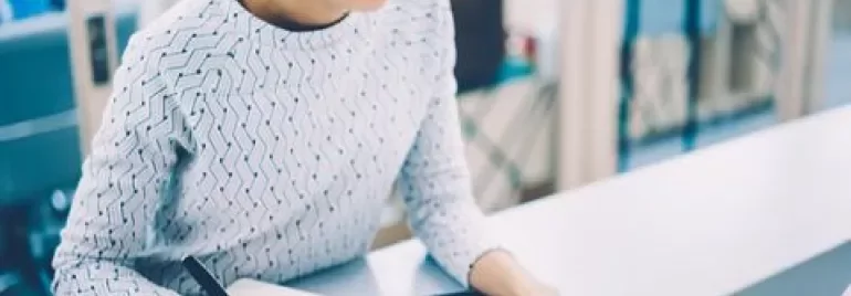 Gözlüklü kadın, dizüstü bilgisayarda çalışıyor, not tutuyor.