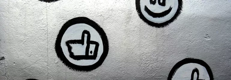 Grafiti olarak kalp, gülen yüz ve beğeni sembolleri; gri duvar üzerinde siyah çerçeveli.