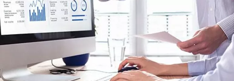 Two people reviewing a financial report on a computer screen.