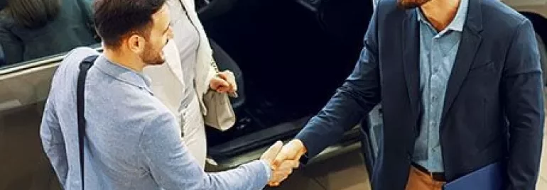 Two men shaking hands while a woman watches.