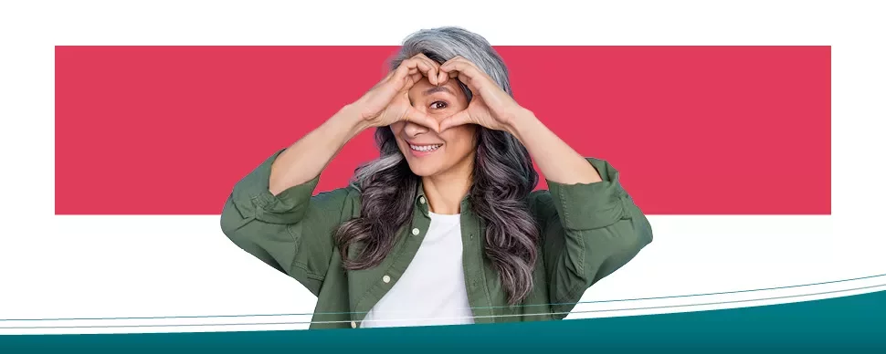 Woman smiling while making a heart shape with her hands.
