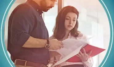 A man and woman reviewing documents in a red folder.