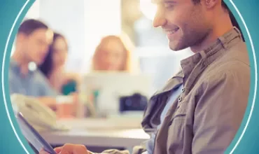 A man using a tablet with coworkers in the background.