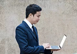 A man on a suit holding a laptop