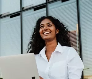 A girl smiling while using a laptop