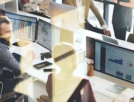 Office workers analyzing data on computer screens.