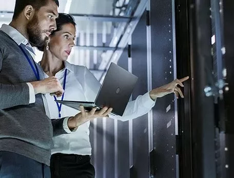 Two people working in a data center with a laptop.
