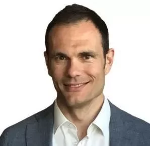 A man in a suit smiling at the camera.