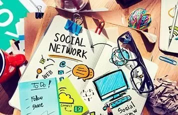 Notebook with social media icons and doodles on a desk.