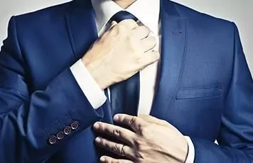 Man adjusting a tie while wearing a blue suit.