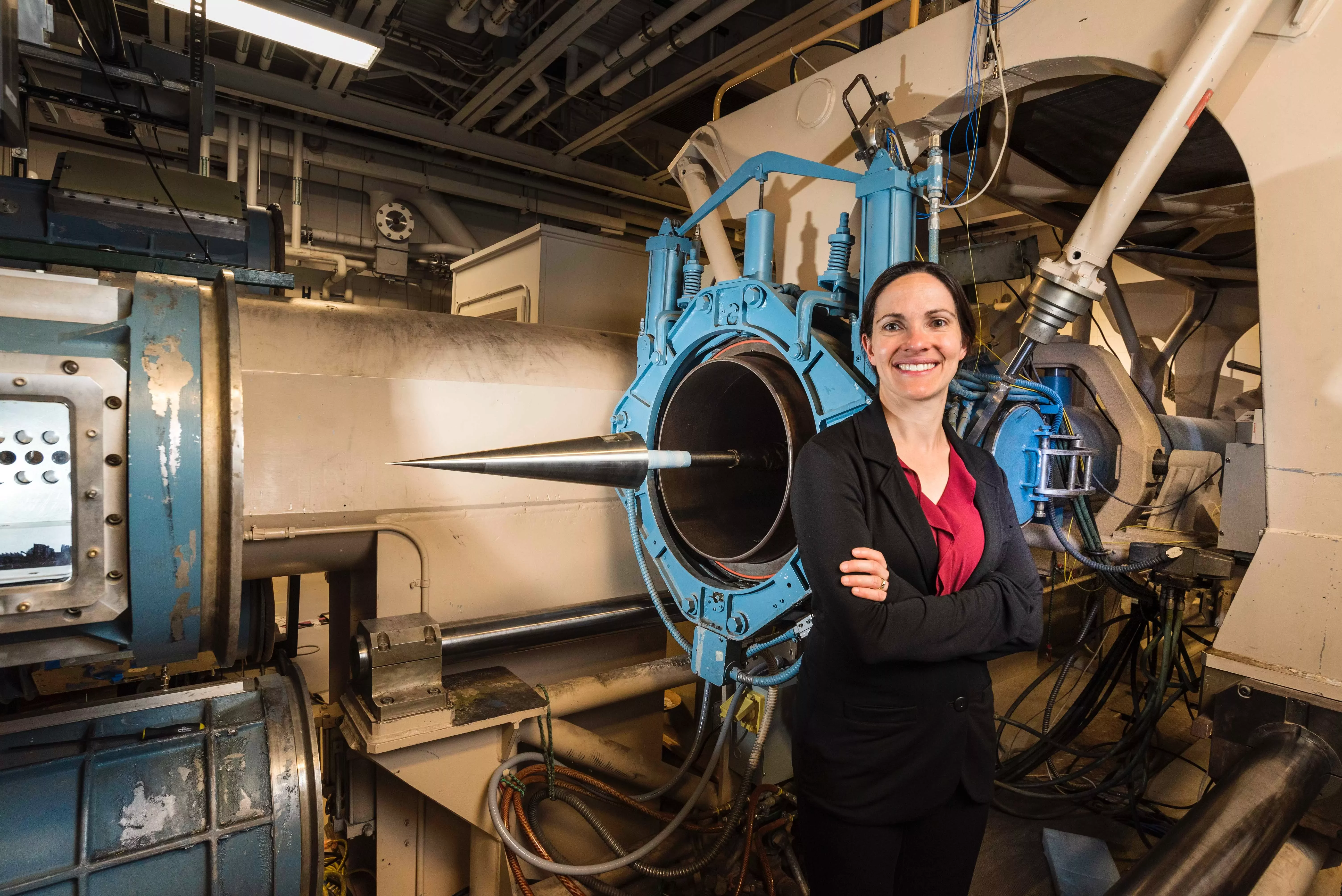 Engineer smiling next to a large machinery setup.