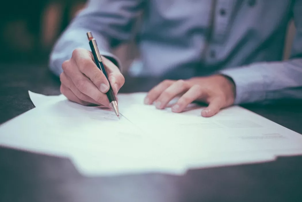 Person writing on papers with a pen.